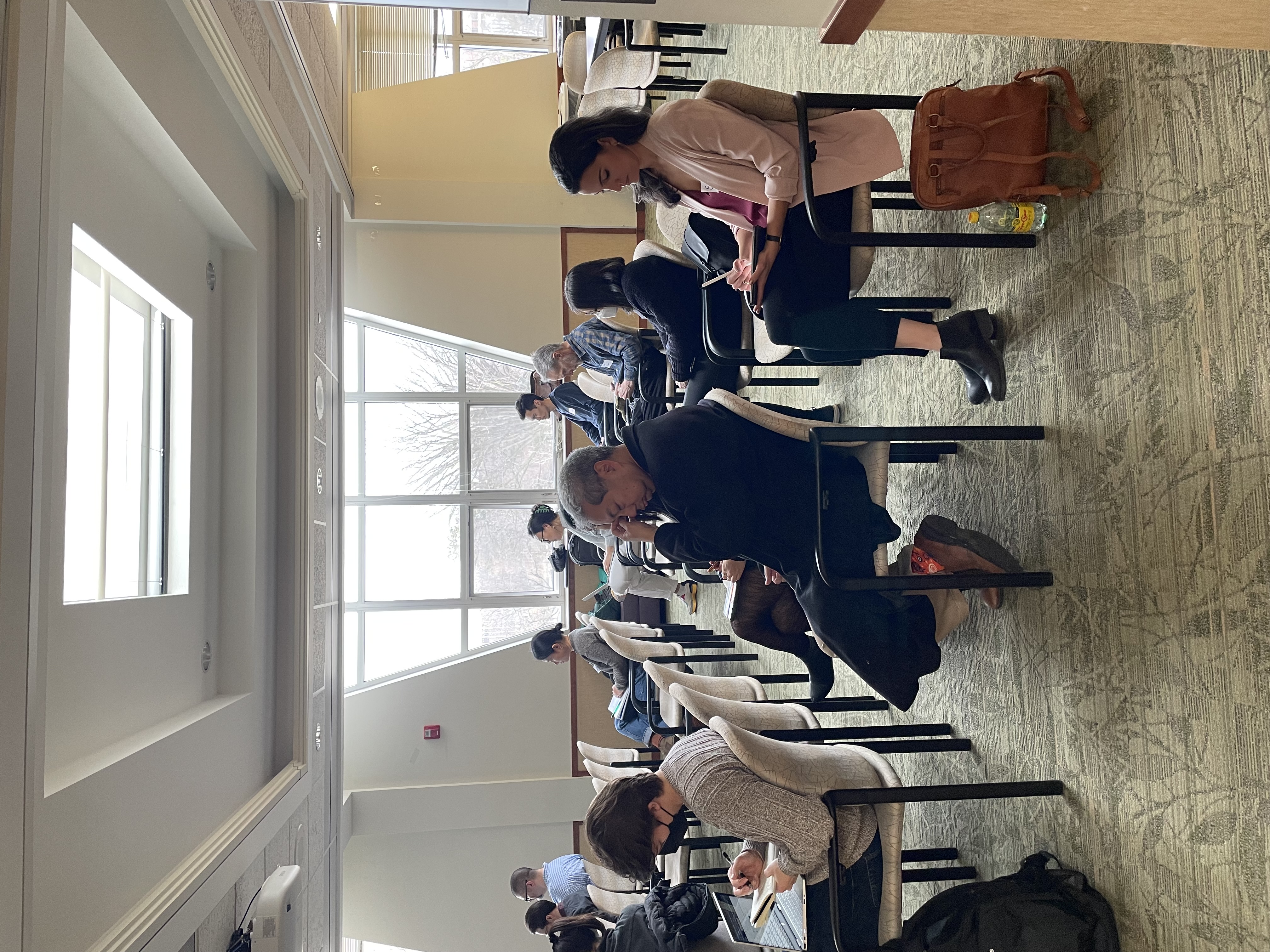participants sit in chairs with a bright window behind